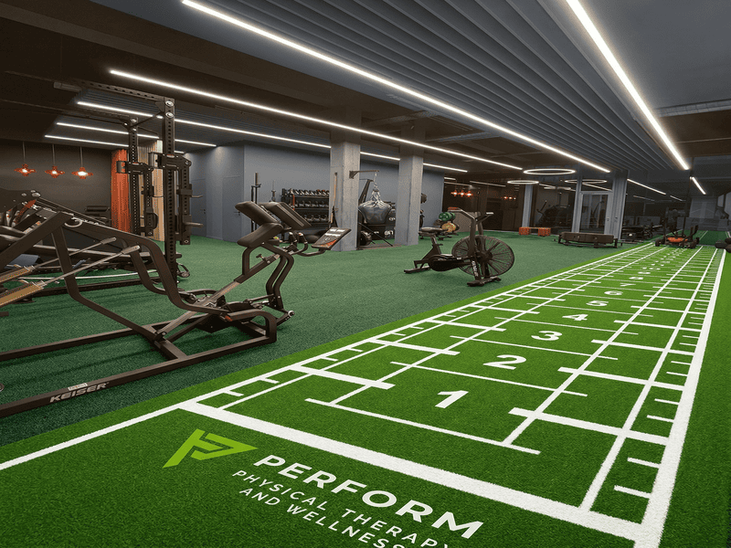 Weighted sled push on green gym turf track